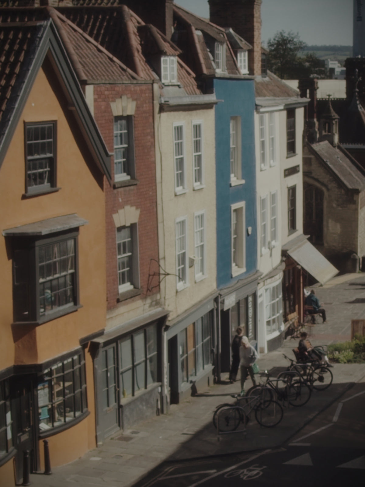 View along Colston Street showing a row of five houses in varied colours, including the Lone Rambler shop frontage.