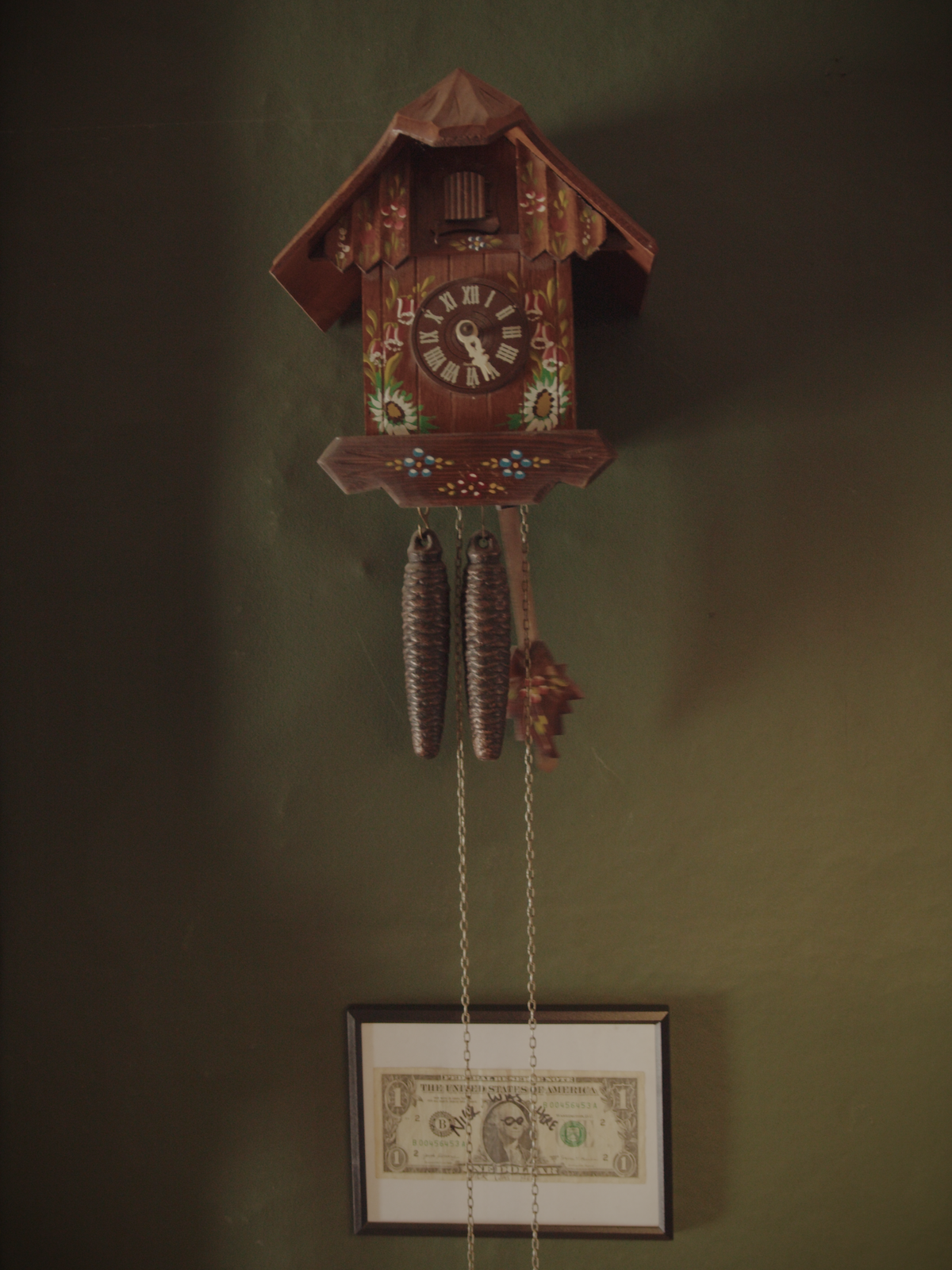 Workshop interior with cuckoo clock and framed one-dollar bill on the wall.