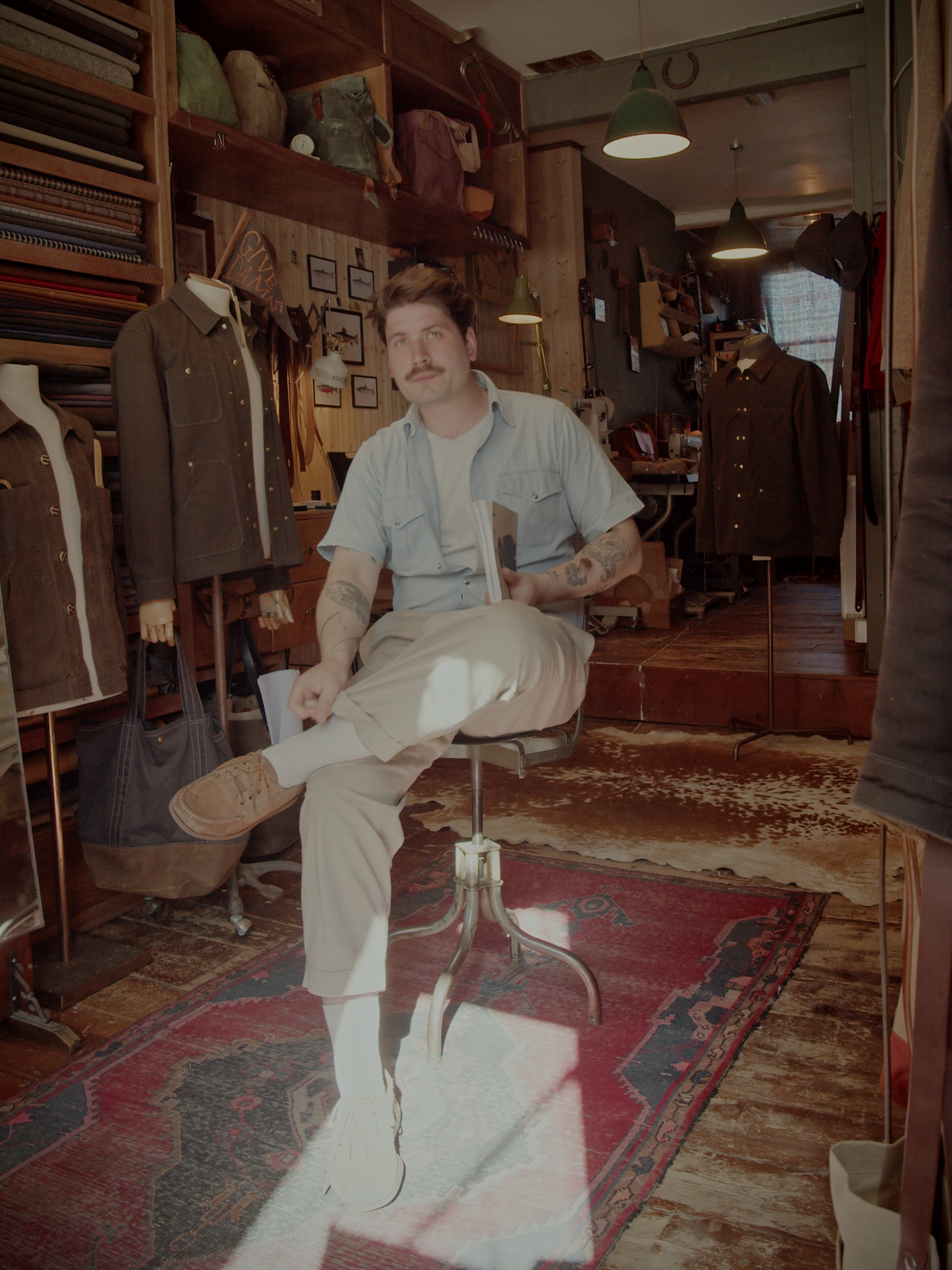 Sitting in workshop on a chair, reading Avant magazine.